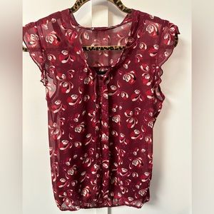 Burgundy/Red sleeveless floral blouse.